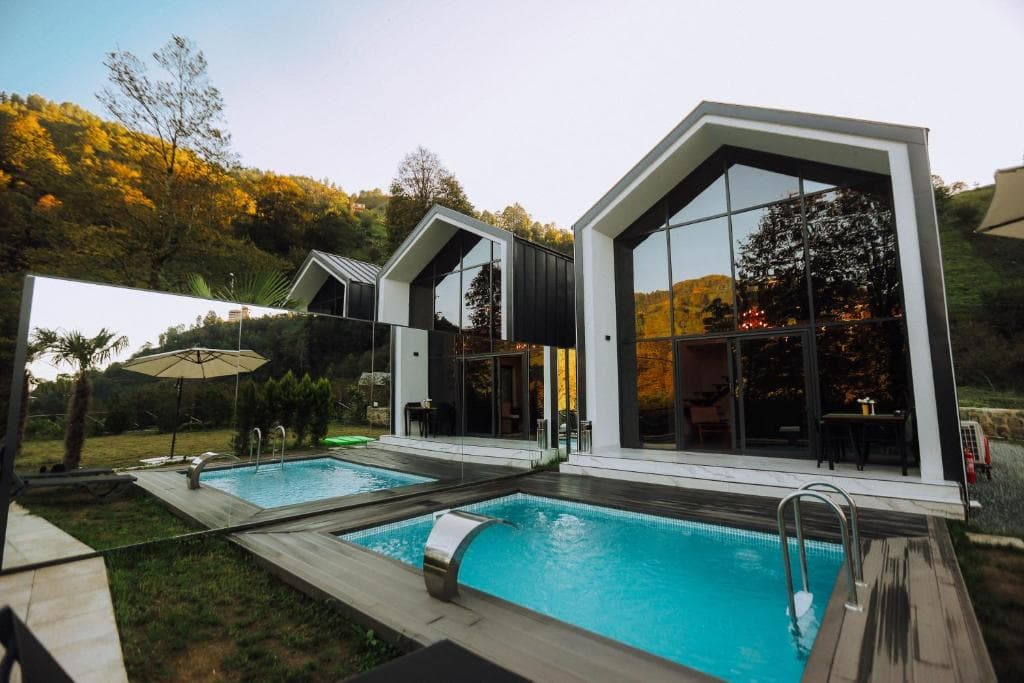 Gün batımında dere kenarındaki Rize Roof Villa bungalovlarının dış görünümü